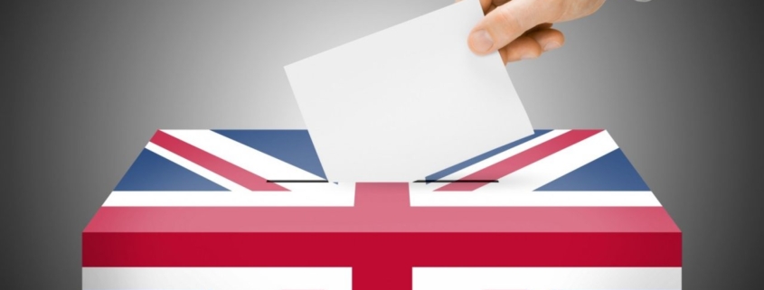 A hand putting a piece of paper into a ballot box.